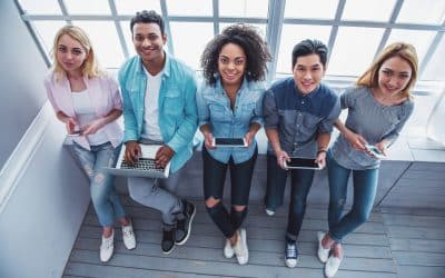 High angle view of young people of different nationalities using gadgets, looking at camera and smiling